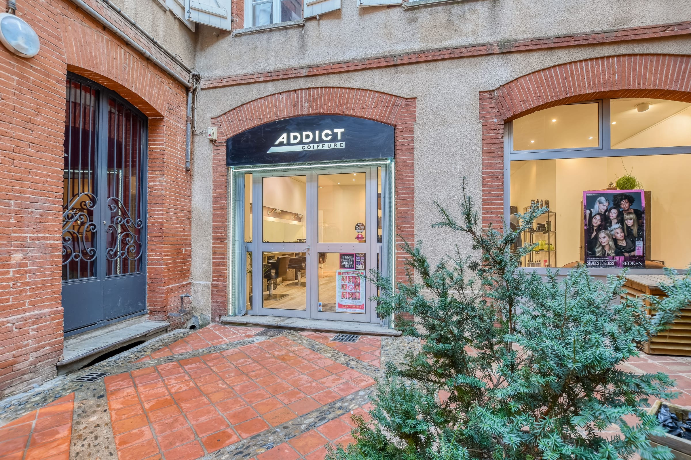 Façade du salon Addict Coiffure sous les arcades en brique, rue Saint-Antoine du T à Toulouse
