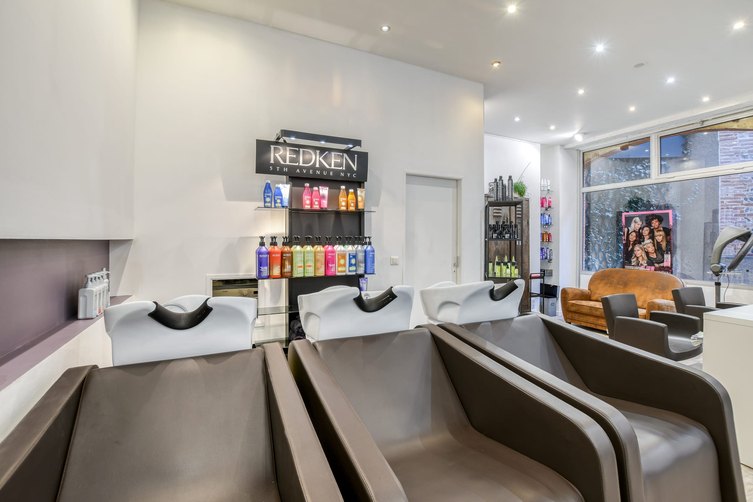 Espace shampoing avec fauteuils confortables et produits Redken